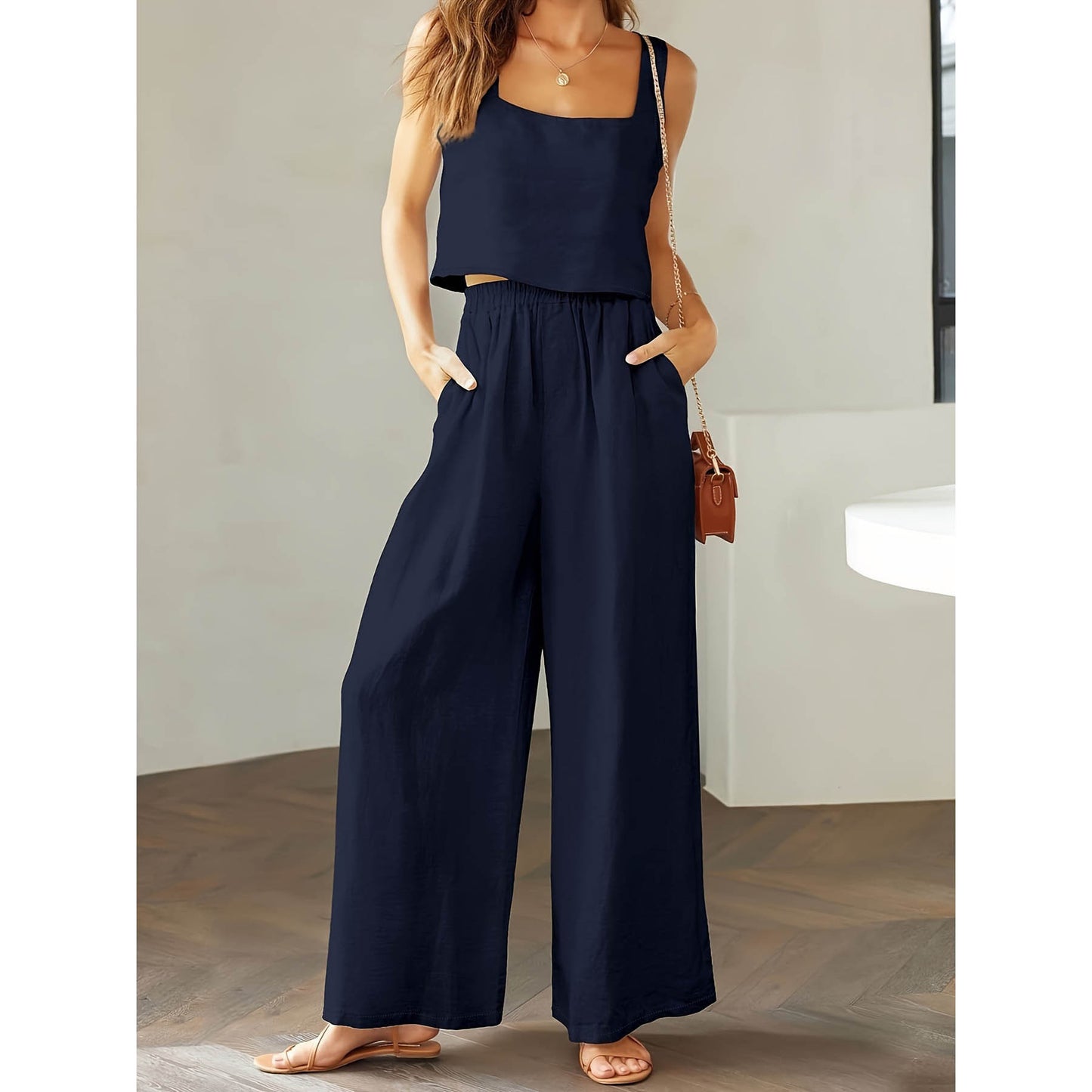 Woman wearing a navy blue jumpsuit with a plain background