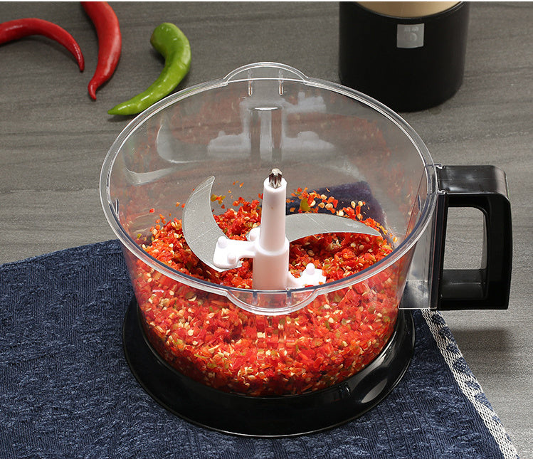 Food processor with ground red peppers on a gray surface
