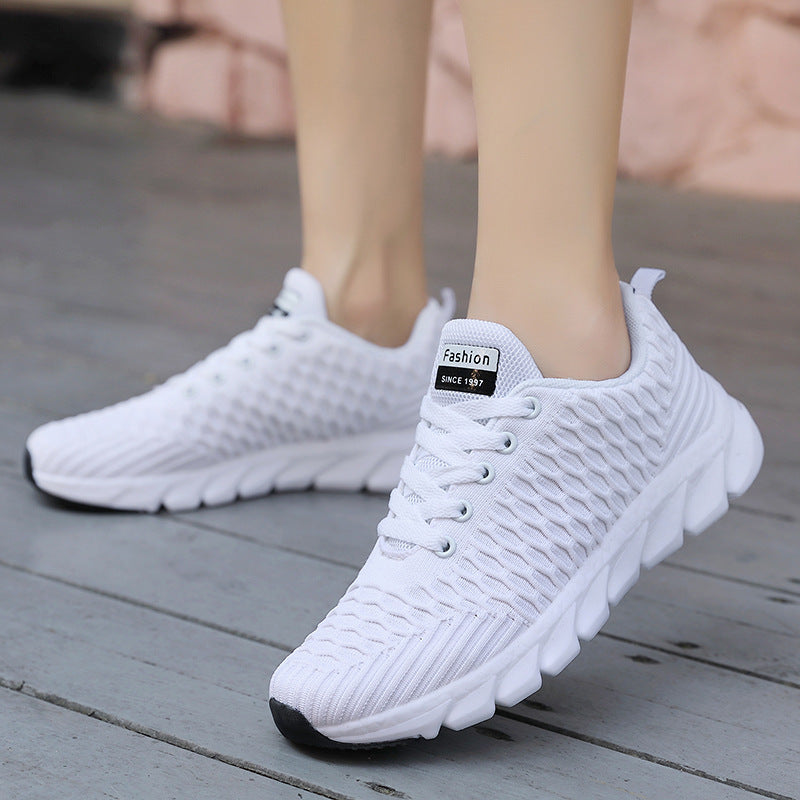White sneakers with a brand label on a wooden floor