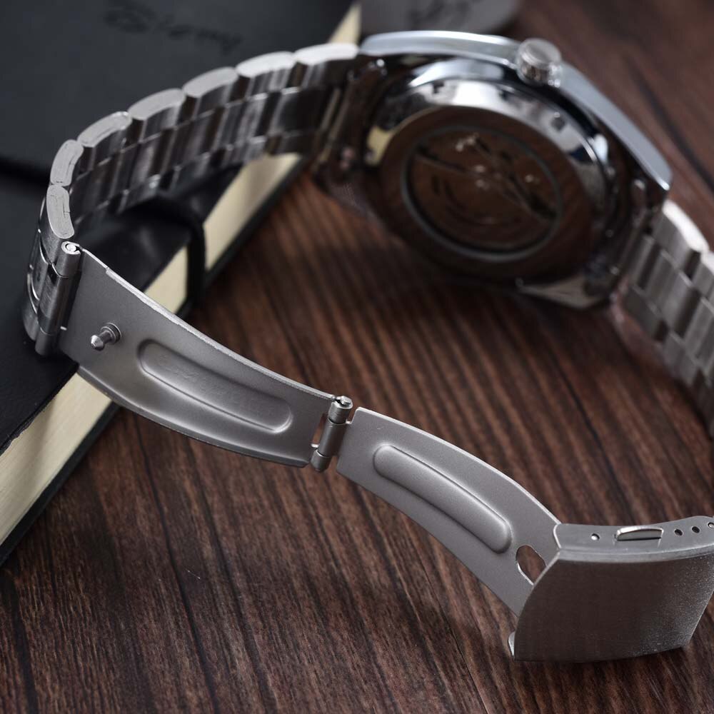 Close-up of a silver metal watch band on a wooden surface