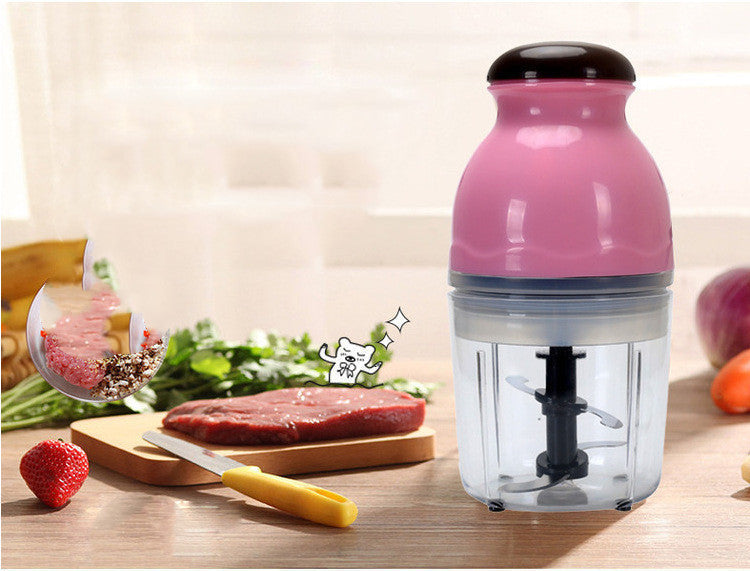 Pink kitchen chopper on a wooden surface with ingredients in the background