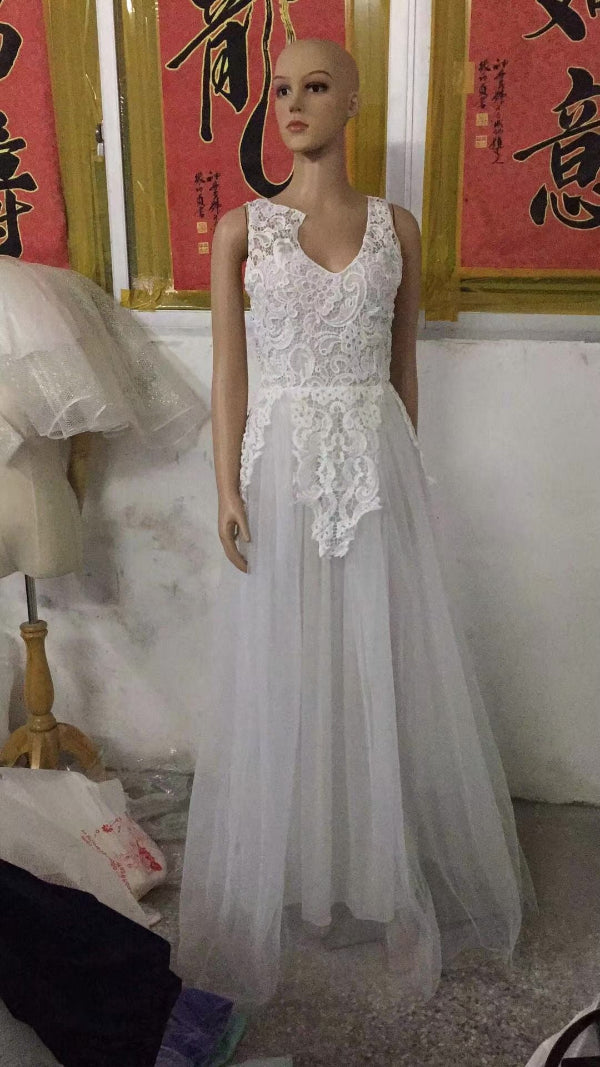 Mannequin wearing a white lace dress in a room with Chinese calligraphy on the wall.