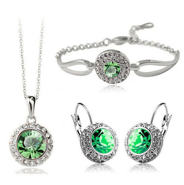 Jewelry set with necklace, bracelet, and earrings featuring green gemstones on a white background.