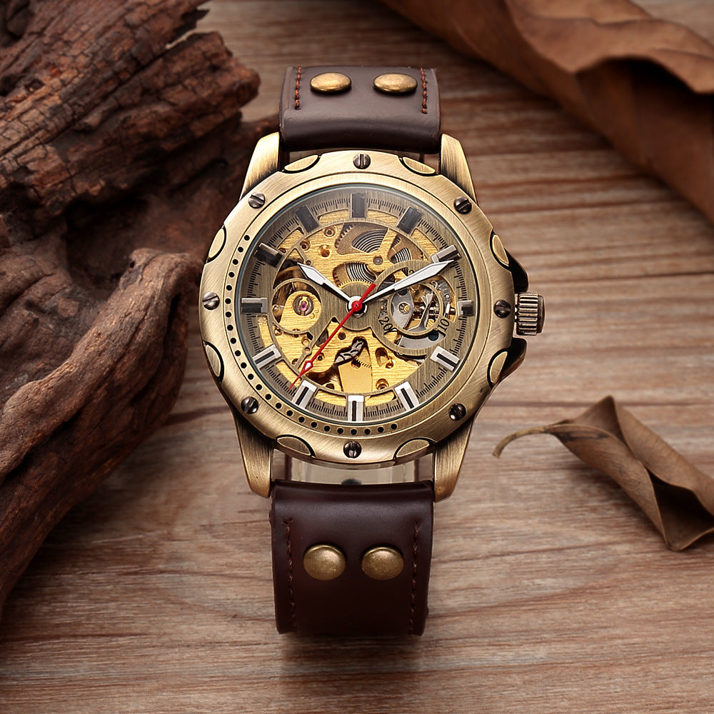Gold mechanical watch with brown leather strap on a wooden surface