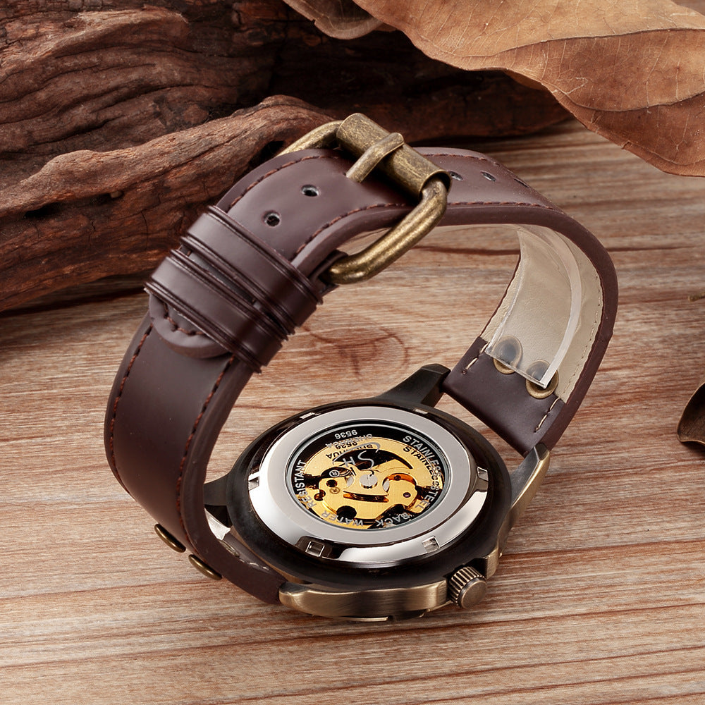 Watch with brown leather strap and visible mechanical components on a wooden surface