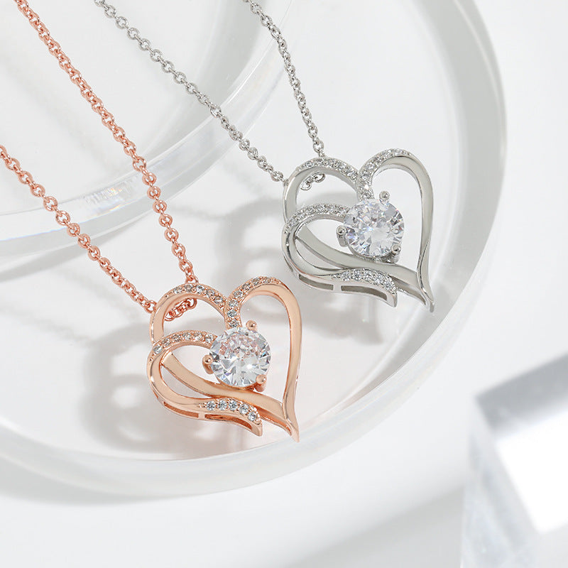 Two heart-shaped diamond pendants on necklaces against a white background