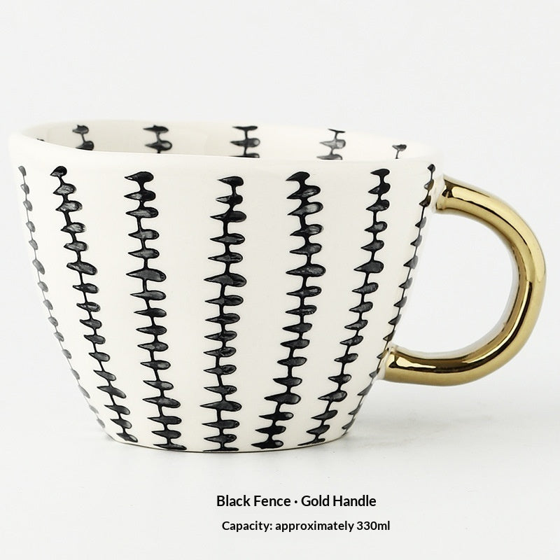 White mug with black wavy pattern and gold handle on a white background