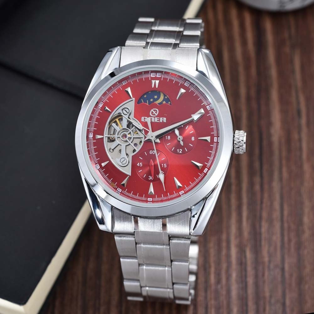 Silver watch with a red face on a wooden surface