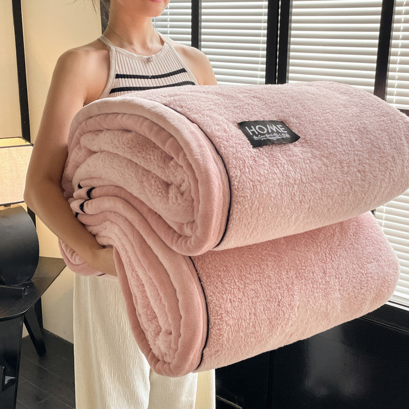 Person holding a pink blanket with a brand label indoors.