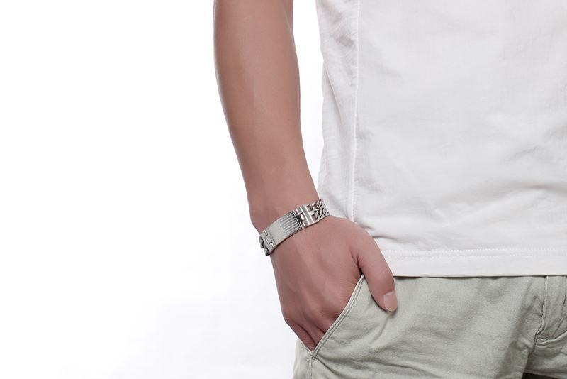 Person wearing a white shirt and beige pants with a silver bracelet on a white background