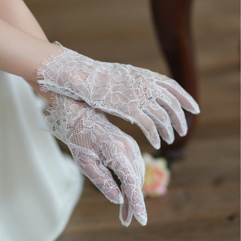 White lace gloves worn by a person with a blurred background