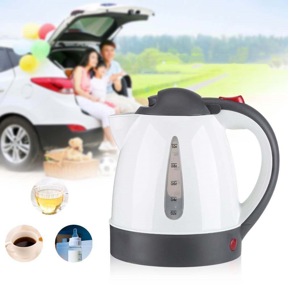 White electric kettle with black handle and base, displayed with a car and people in the background.