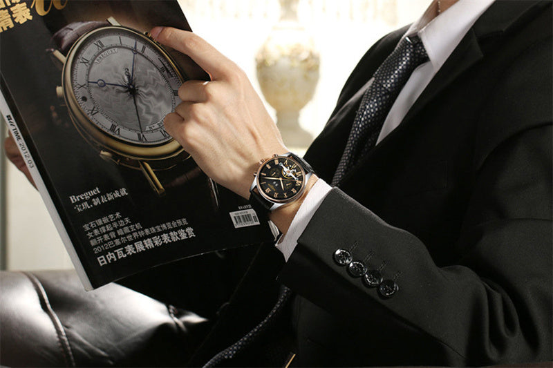 Person wearing a watch with a magazine featuring a Breguet watch on a blurred background
