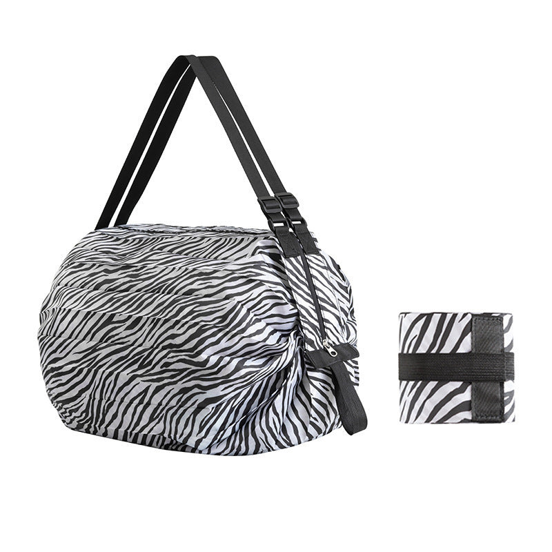 Foldable reusable zebra-striped nylon shopping tote with shoulder straps and pouch
