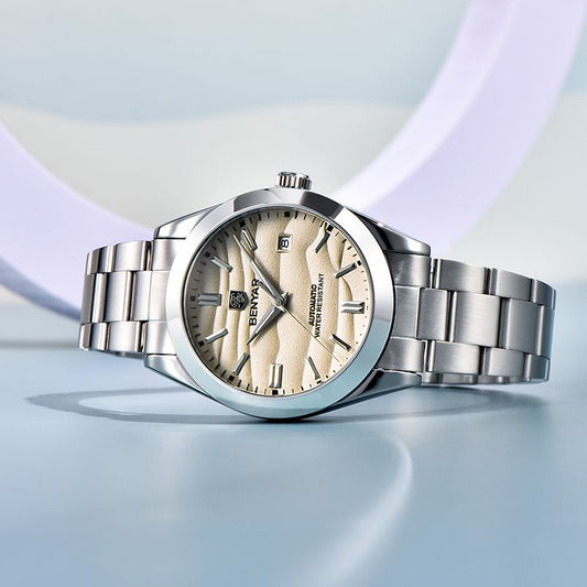 Silver watch with a beige face on a light blue background
