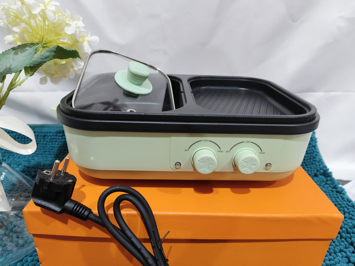 Portable grill on an orange stand with a white background
