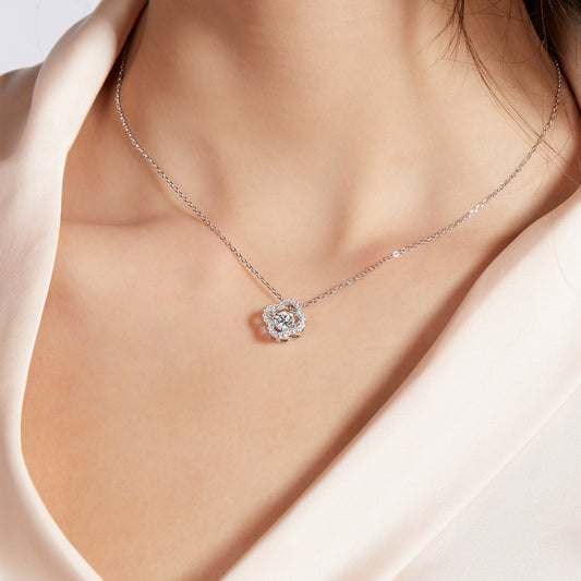 Silver necklace with a floral pendant on a person wearing a light pink top.