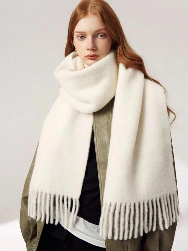 Woman wearing a white scarf with fringes on a plain background