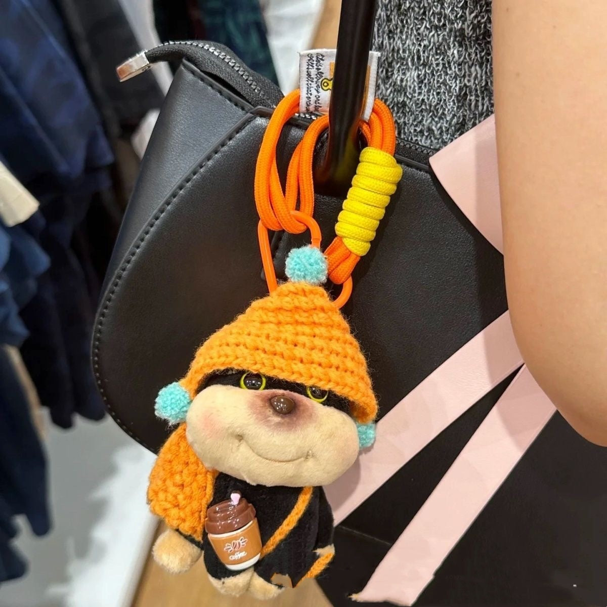 Plush keychain with a character wearing an orange hat and holding a jar, attached to a bag.