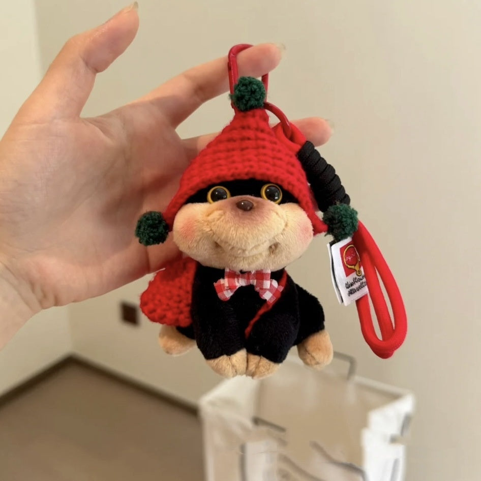 Plush keychain with red hat and black outfit held by a hand against a neutral background