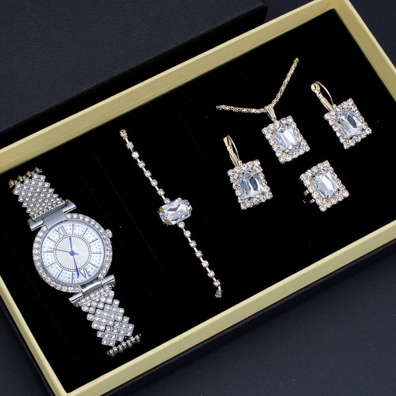 Silver jewelry set including a watch and earrings on a black display box.