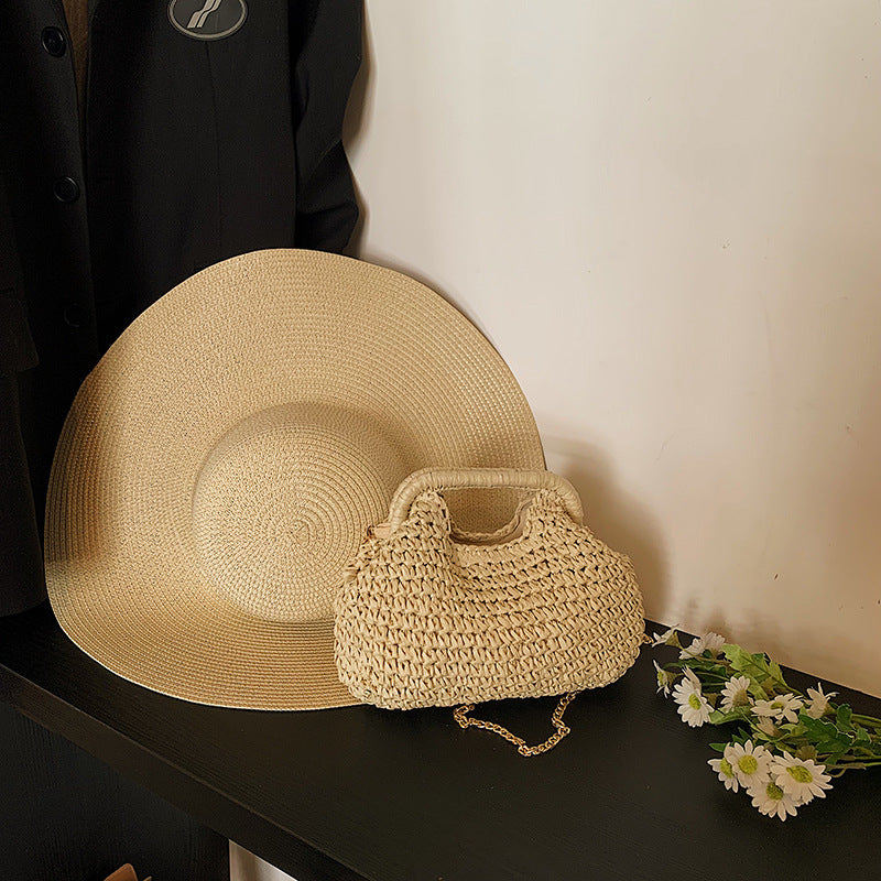 Beige straw hat and handbag on a dark surface with flowers