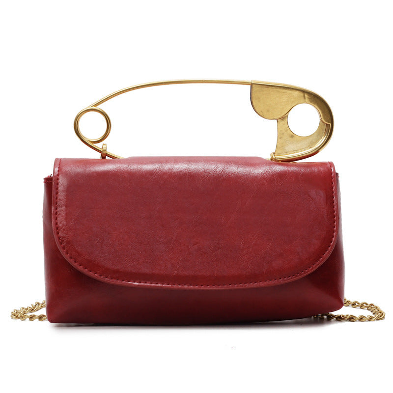 Red handbag with a gold handle and chain on a white background