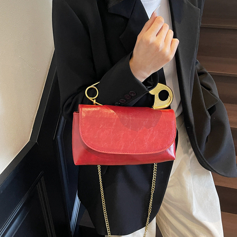 Person holding a red handbag with gold chain strap