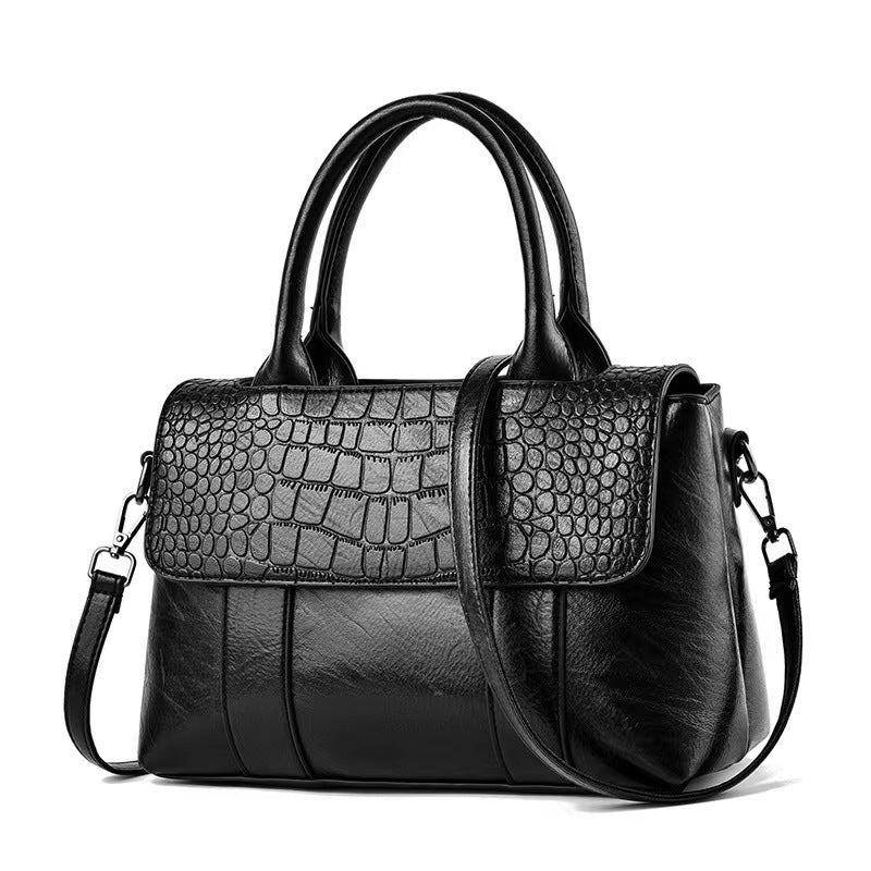 Black handbag with crocodile texture on a white background