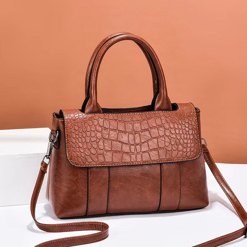Brown handbag with crocodile texture on a white surface with a brown background