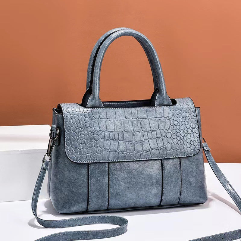 Blue textured handbag with a strap on a white surface and brown background