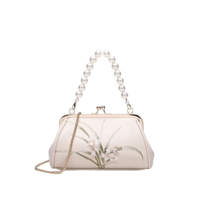 White handbag with floral design and pearl handle on a white background