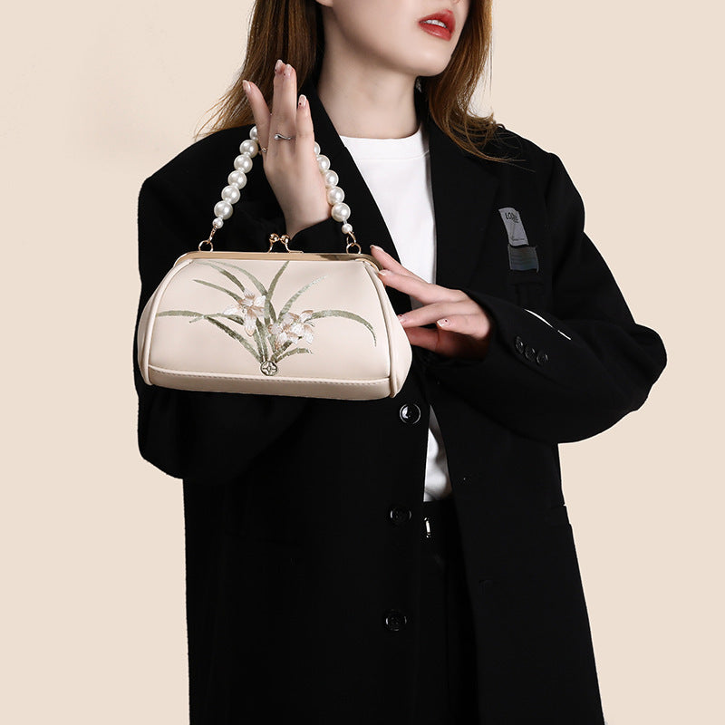 Woman holding a beige handbag with floral design against a beige background
