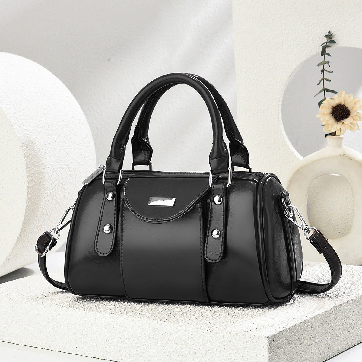 Black handbag on a white surface with a neutral background