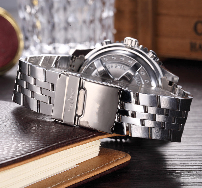 Silver watch with a detailed face on a wooden surface