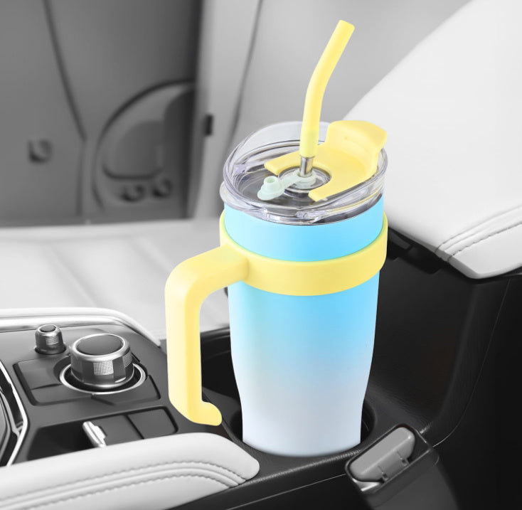 Gradient blue to yellow tumbler with handle and straw in a car cup holder.