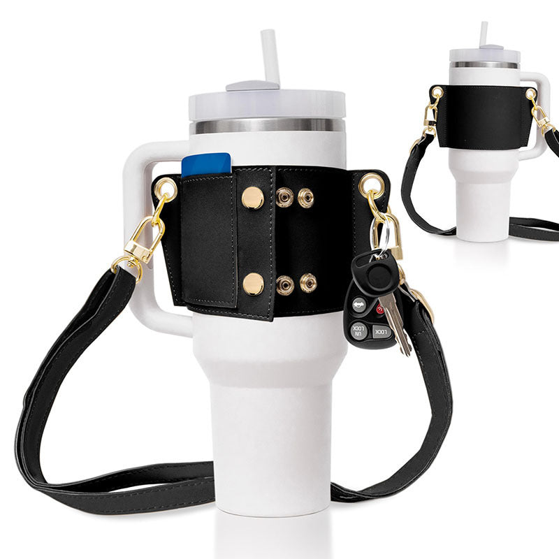 White tumbler with black leather holder, keychain, and strap on a white background