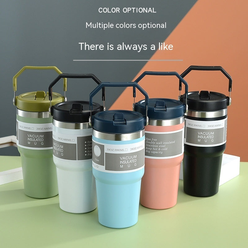 Set of five vacuum insulated tumblers in various colors on a green surface.