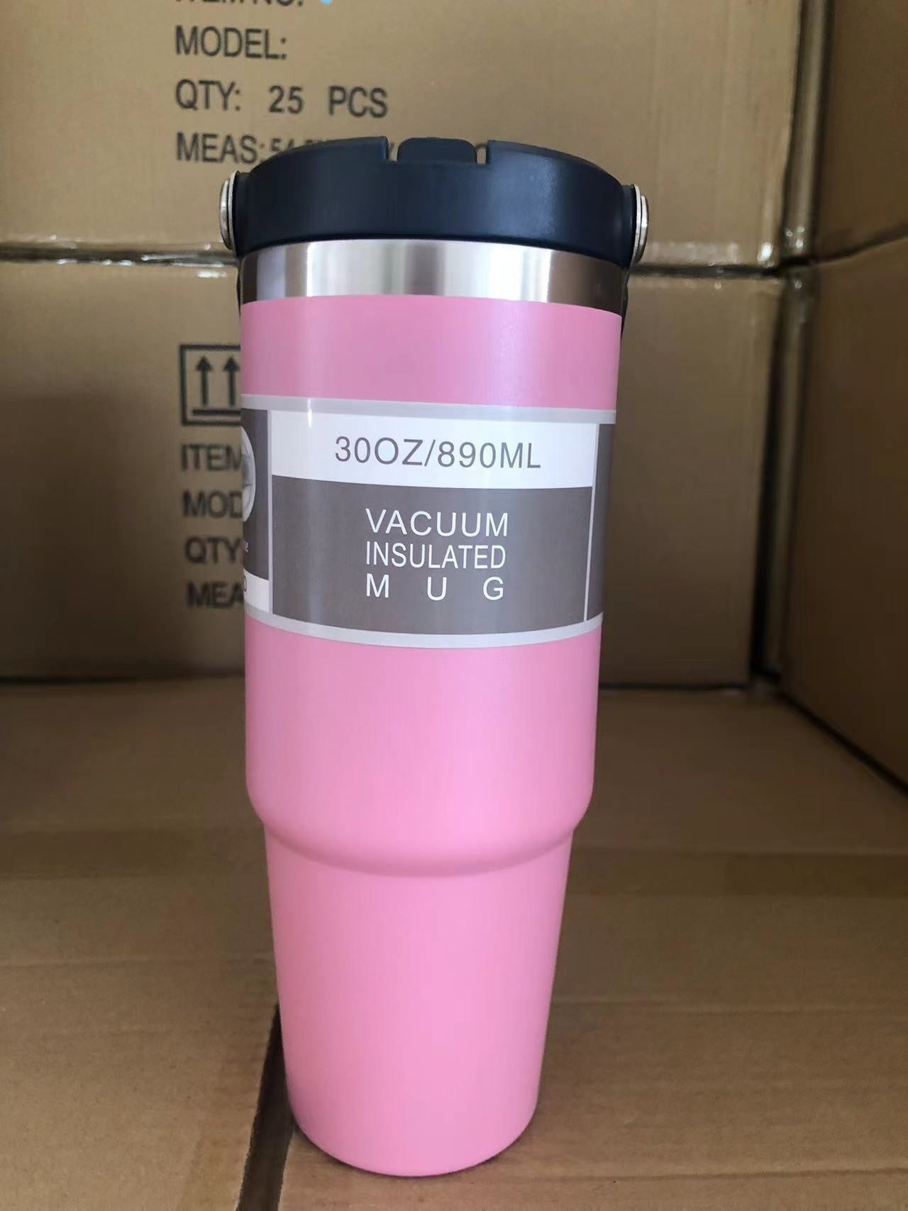Pink vacuum insulated mug with black lid on a cardboard background