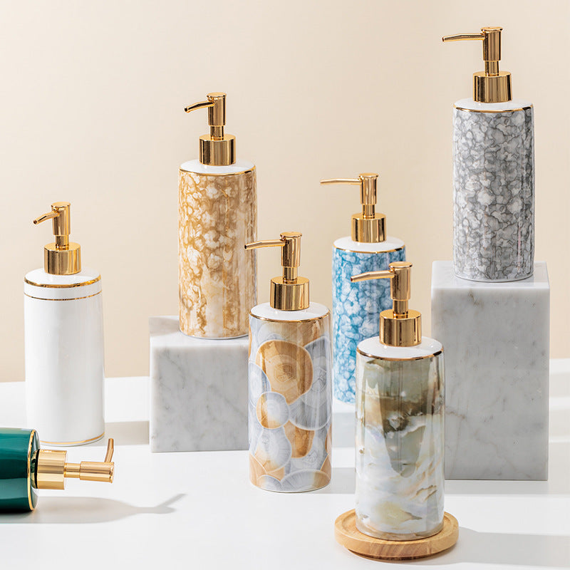 Set of marble-textured soap dispensers with gold pumps on a neutral background