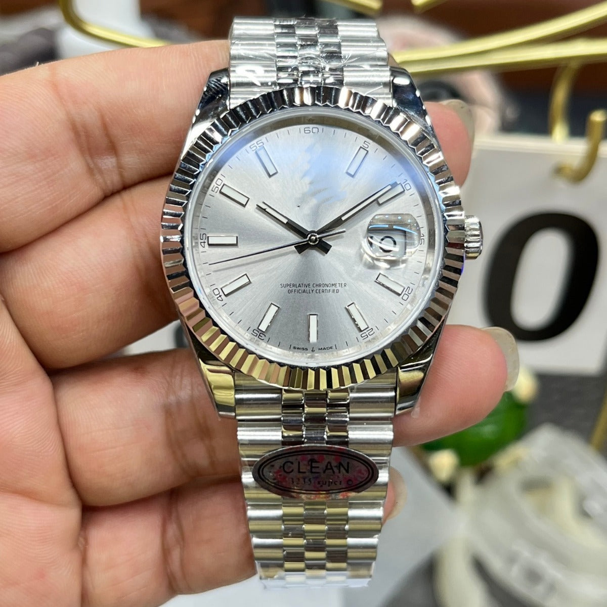 Silver and gold watch held in a hand with a blurred background