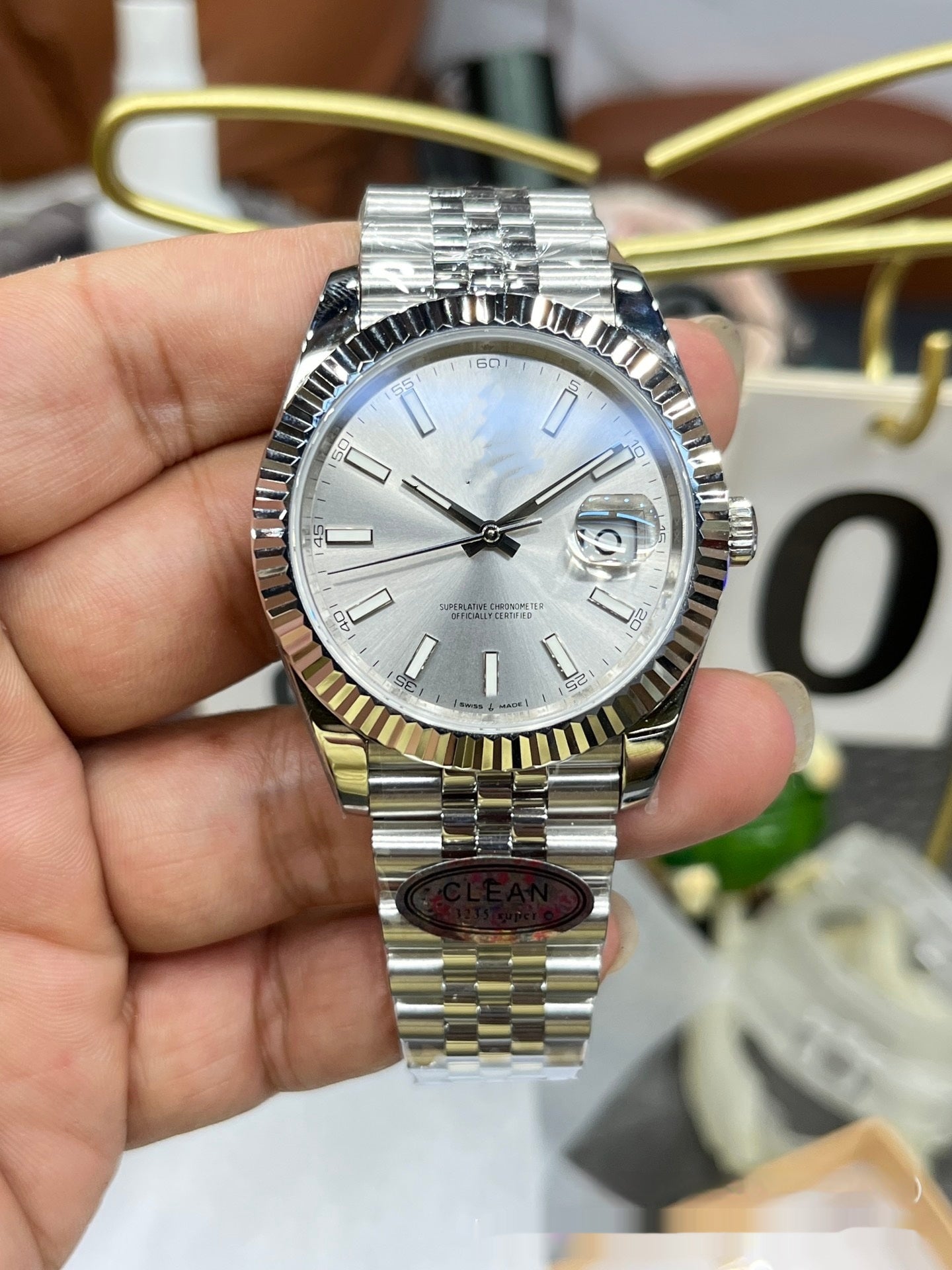 Silver and gold watch held in a hand with blurred background