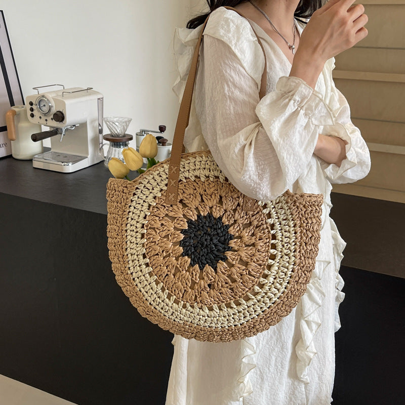 Person holding a round woven bag with a sunflower design in a kitchen setting