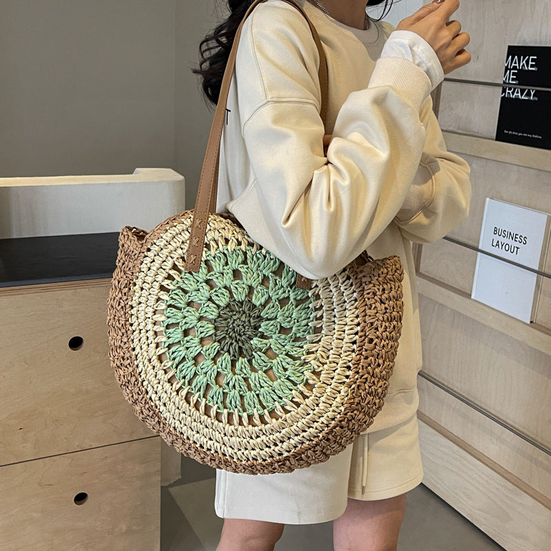 Person holding a round woven bag with a green crochet top in an indoor setting.
