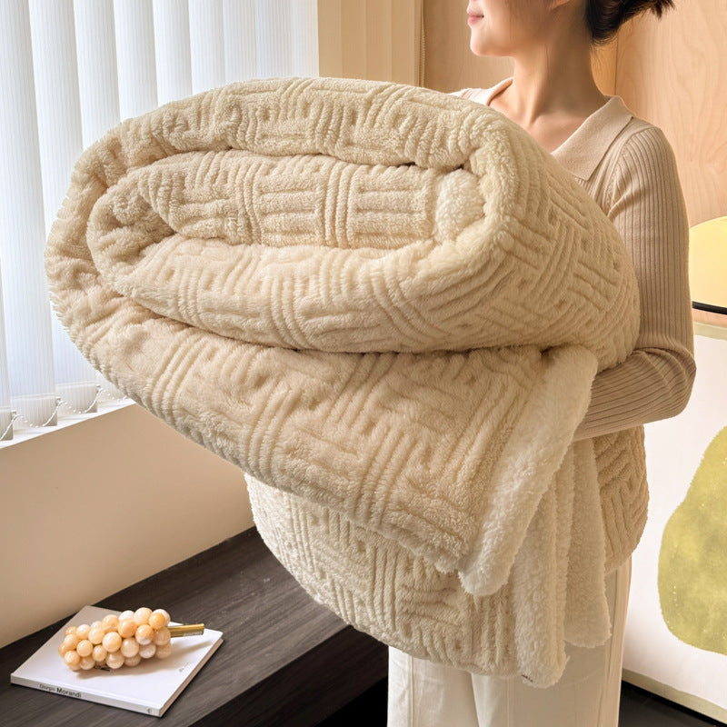 Person holding a large beige textured blanket in a room with a window and decorative items.
