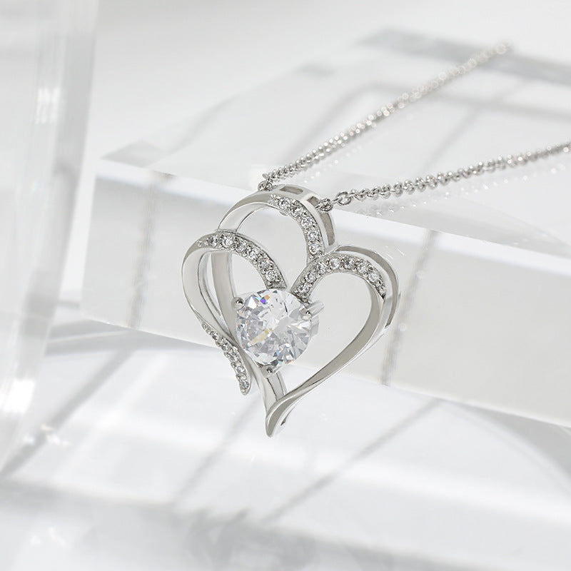 Silver heart-shaped necklace with a clear gemstone on a white background