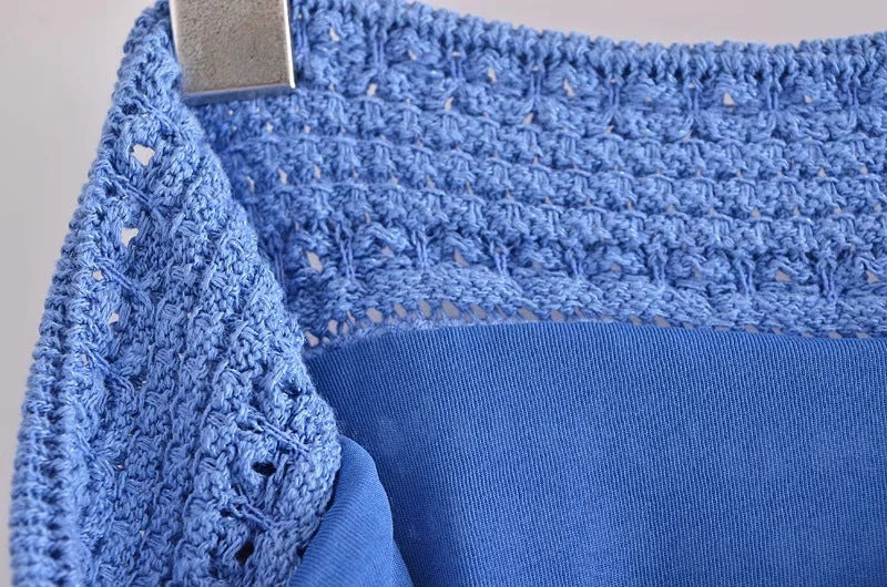 Close-up of a blue garment with lace detailing on a neutral background