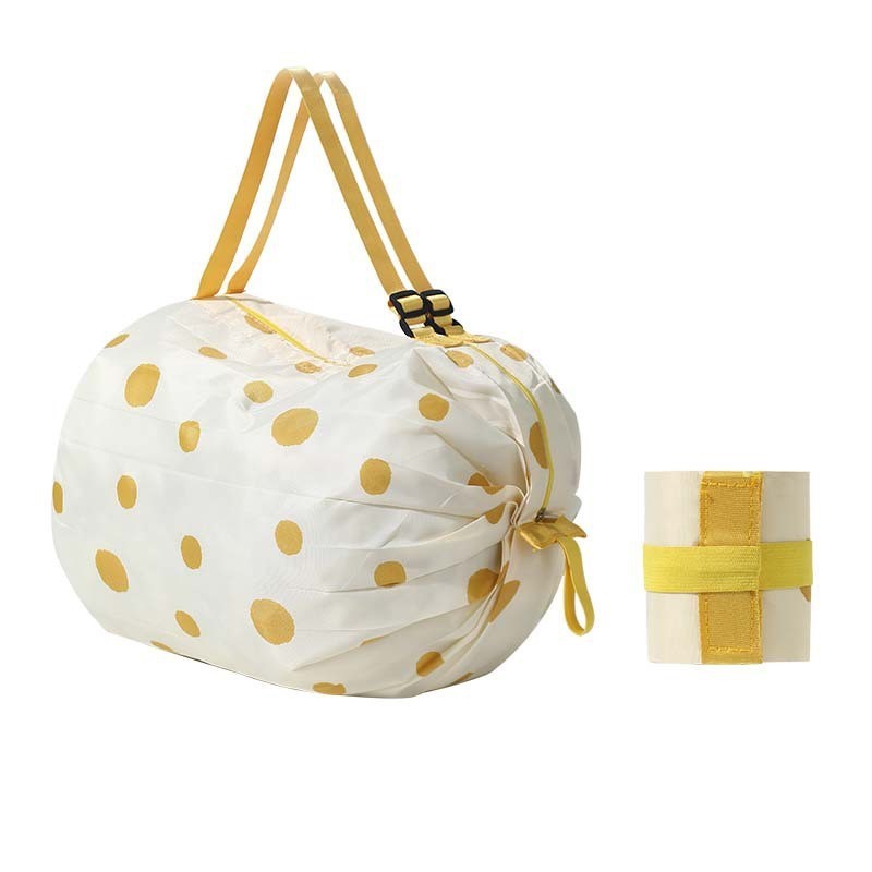 Foldable nylon tote bag, white with yellow dot print and yellow carry handles.