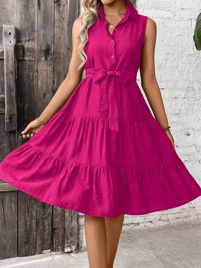 Woman wearing a bright pink dress against a rustic wooden and white brick wall.