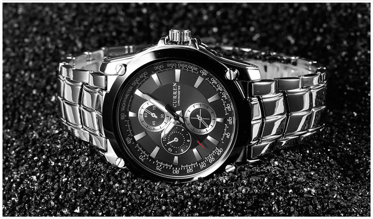 Silver watch with a black face on a dark textured background